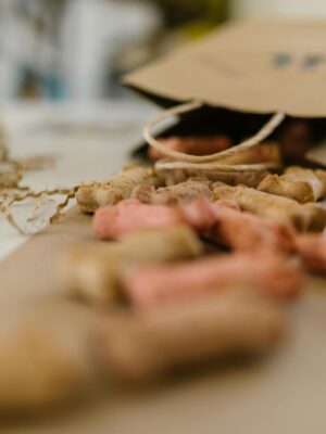 A paper bag spilling colorful dog treats amidst shredded confetti on a table.